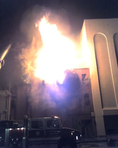 The building fire extends over the fire truck below.